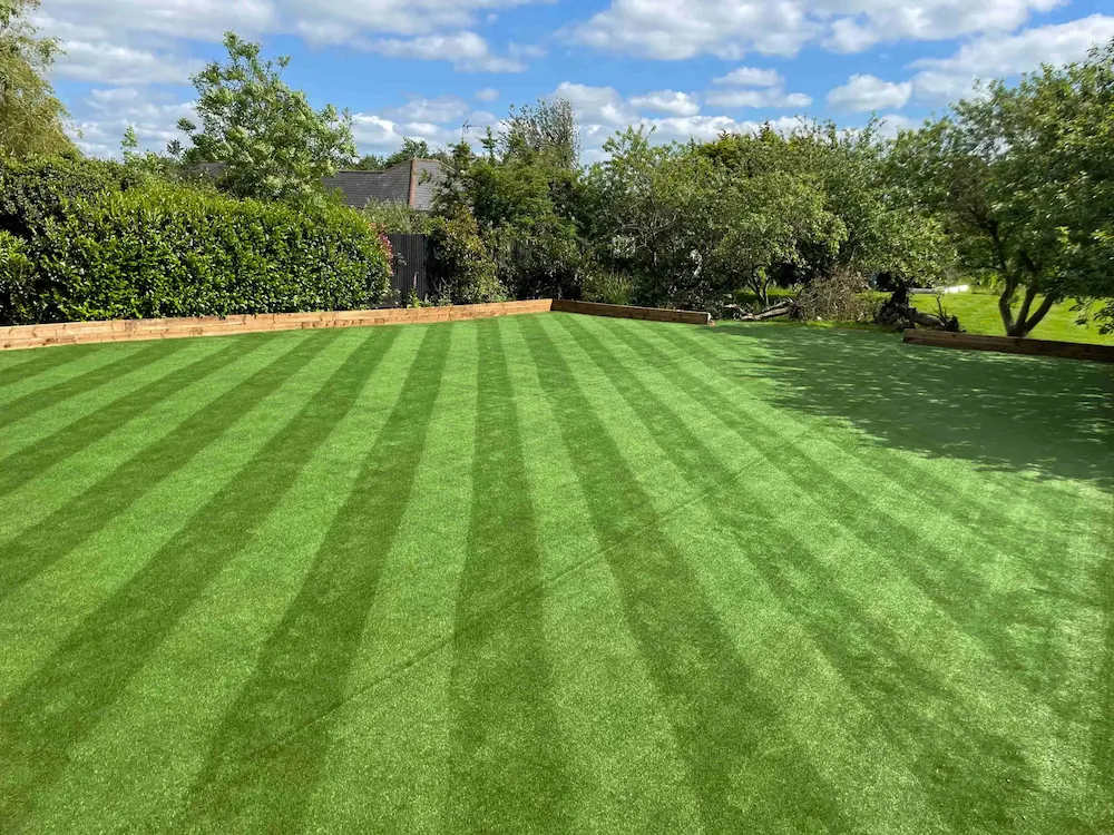 Professional artificial grass installation by Look Real Lawns showing striped lawn pattern in garden